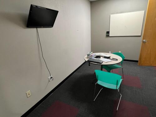 Office with Contents &ndash; Wall-Mounted Asus Monitor, Round Table, (2) Plastic Chairs, Whiteboard